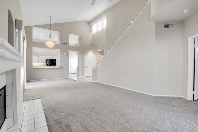 unfurnished living room featuring ceiling fan, light colored carpet, high vaulted ceiling, and a tiled fireplace