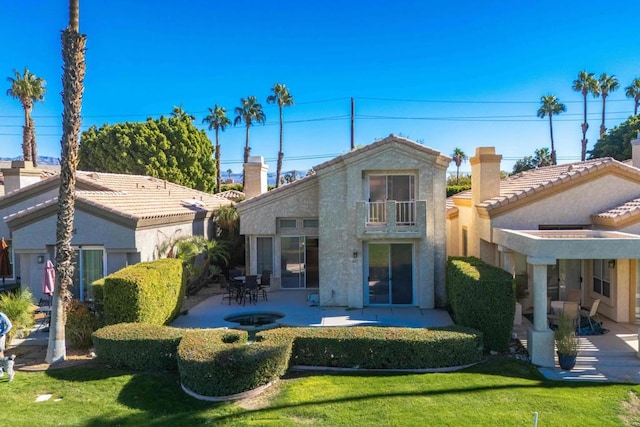 rear view of house featuring a patio, a balcony, and a lawn