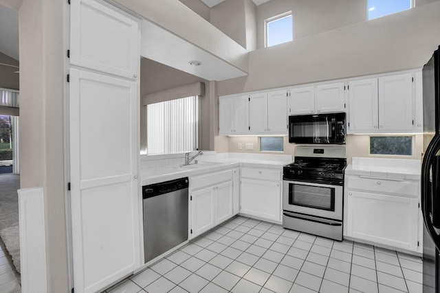 kitchen featuring a towering ceiling, stainless steel appliances, and plenty of natural light