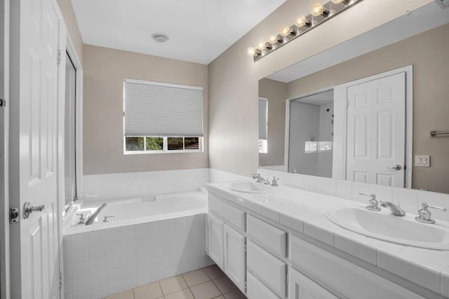 bathroom with vanity, a relaxing tiled tub, and tile patterned floors