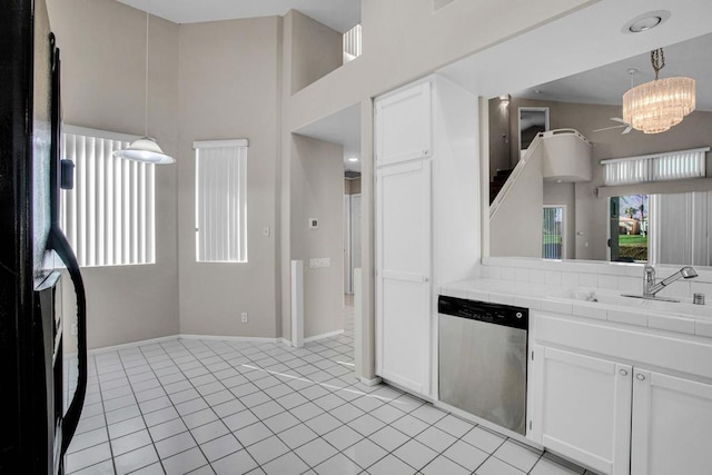 kitchen with tile countertops, white cabinets, stainless steel dishwasher, and hanging light fixtures