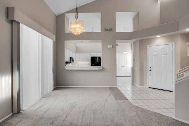 unfurnished living room featuring a notable chandelier, light carpet, and high vaulted ceiling