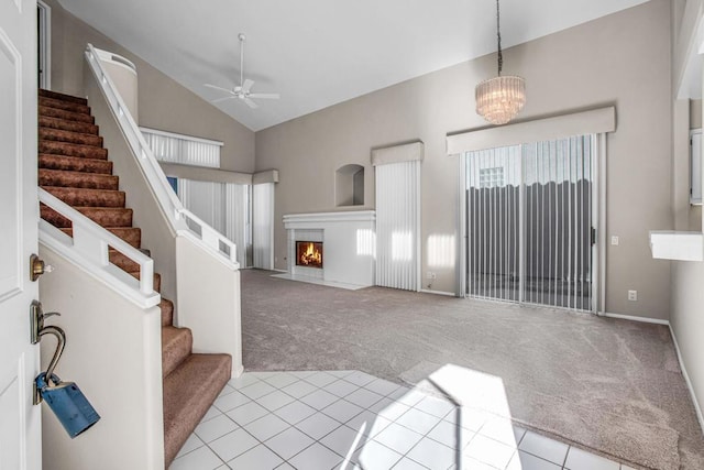 entrance foyer with ceiling fan with notable chandelier, light colored carpet, and high vaulted ceiling