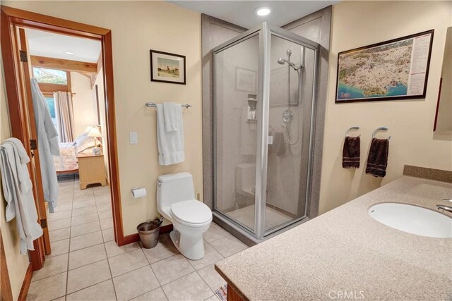 bathroom with toilet, a shower with door, tile patterned floors, and vanity