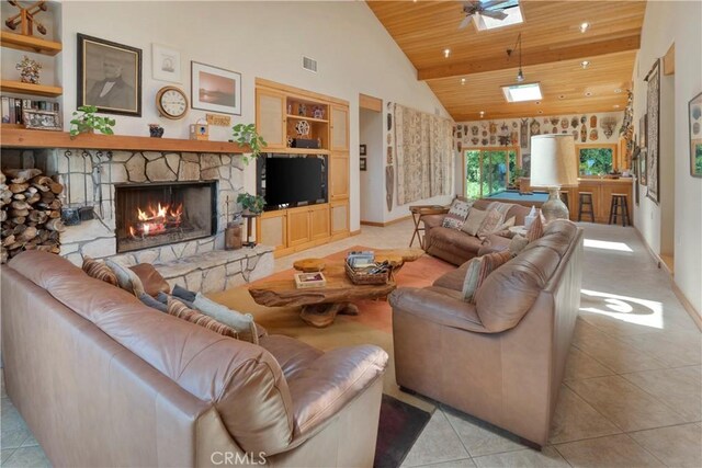 living room with light tile patterned flooring, a skylight, built in features, wood ceiling, and a stone fireplace