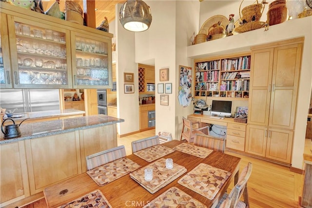 dining space with a high ceiling and light hardwood / wood-style flooring