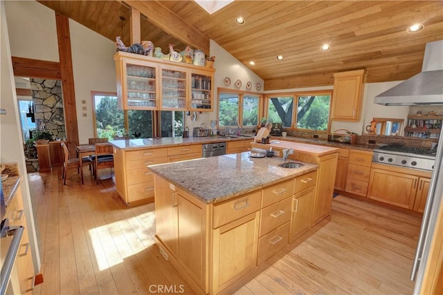 kitchen featuring wooden ceiling, stainless steel appliances, a kitchen island with sink, light brown cabinetry, and wall chimney exhaust hood