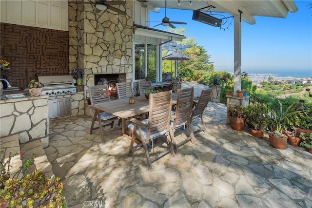 view of patio featuring area for grilling, ceiling fan, and an outdoor stone fireplace