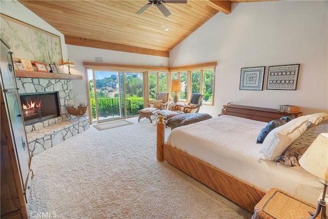 carpeted bedroom with ceiling fan, beam ceiling, a stone fireplace, and multiple windows