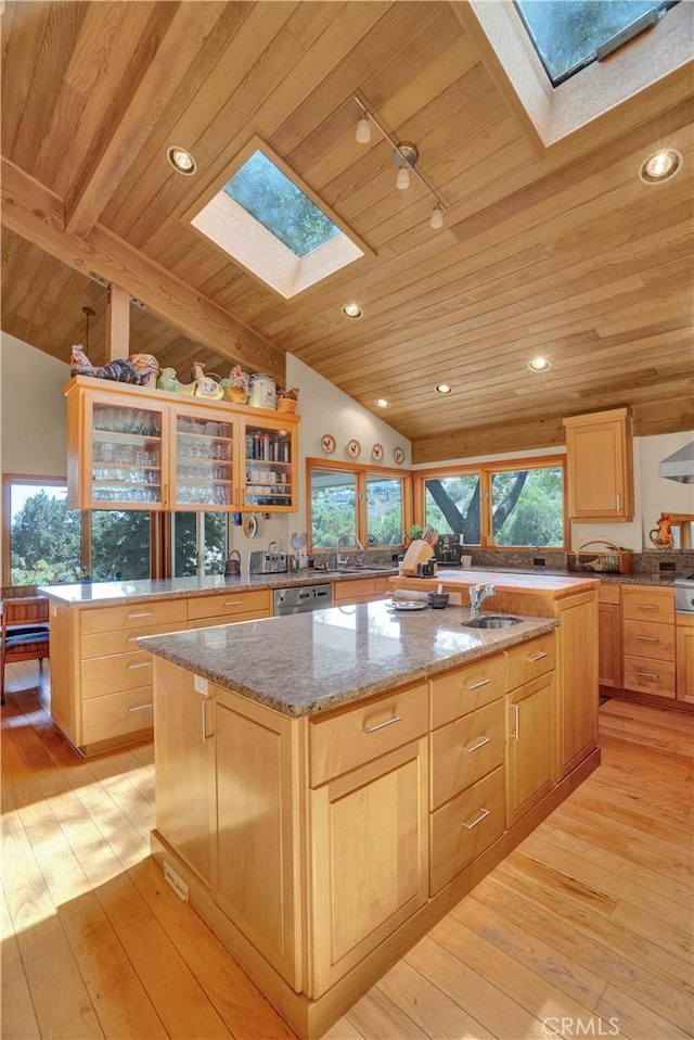 kitchen with light stone countertops, an island with sink, light wood-type flooring, wooden ceiling, and lofted ceiling with skylight