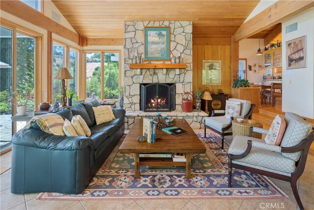 tiled living room with vaulted ceiling, wood walls, a stone fireplace, and wooden ceiling