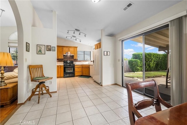 kitchen with sink, vaulted ceiling, white fridge with ice dispenser, black gas range oven, and tasteful backsplash