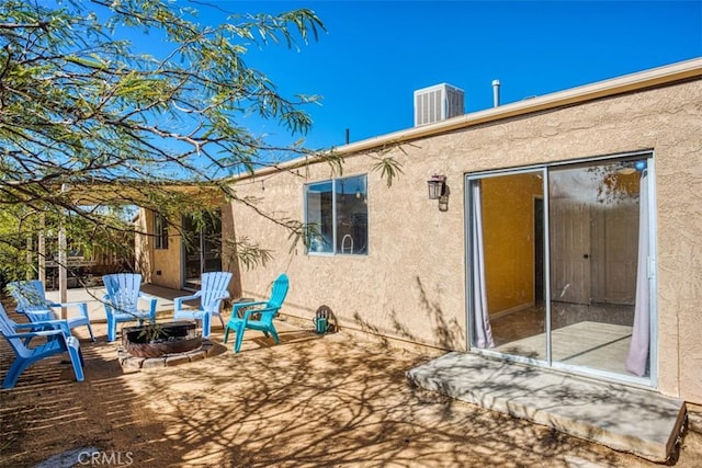 back of property with a fire pit, central AC unit, and a patio