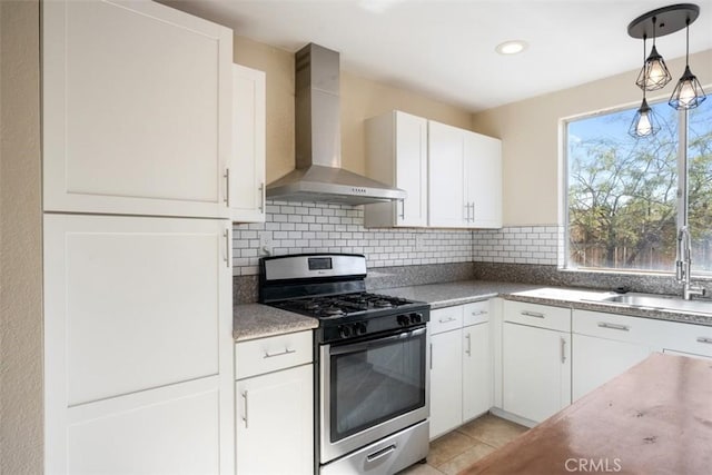 kitchen with backsplash, wall chimney exhaust hood, sink, white cabinets, and stainless steel gas stove