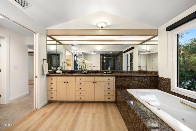 bathroom with hardwood / wood-style floors, vanity, lofted ceiling, and independent shower and bath