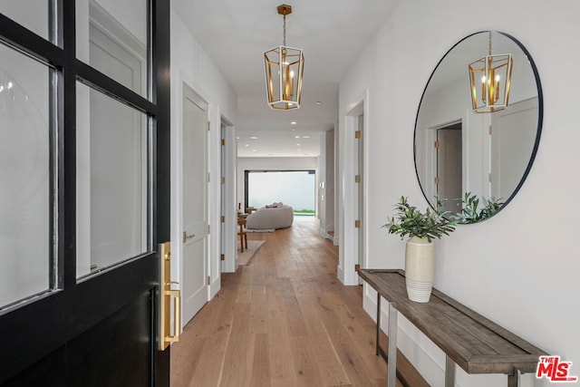 hallway featuring a chandelier and light wood-type flooring