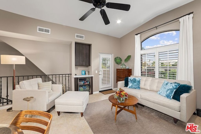 living room with ceiling fan, light tile patterned flooring, beverage cooler, and lofted ceiling