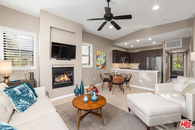 living room featuring ceiling fan, light tile patterned floors, sink, and vaulted ceiling