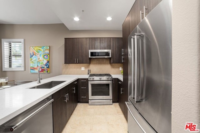 kitchen featuring sink, light tile patterned floors, stainless steel appliances, and dark brown cabinets