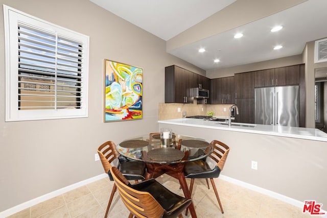 tiled dining area featuring sink and lofted ceiling