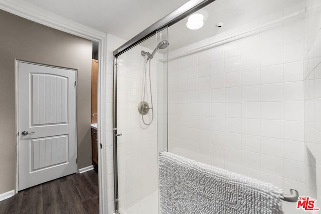 bathroom with hardwood / wood-style floors, vanity, and a shower with shower door