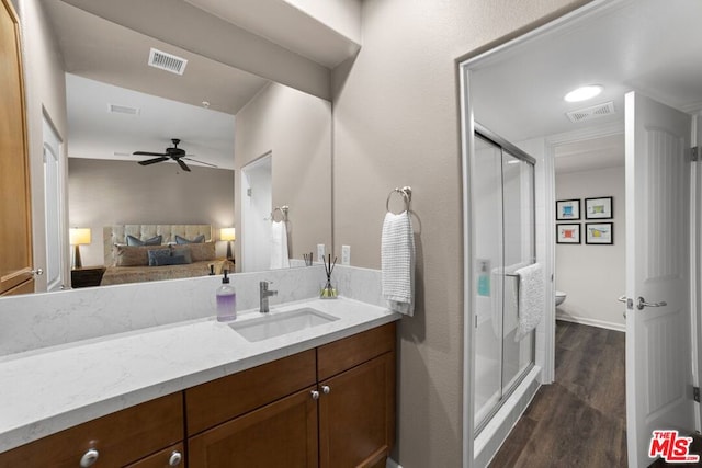 bathroom with hardwood / wood-style floors, a shower with door, toilet, and ceiling fan