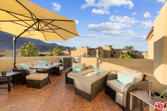 view of patio with a mountain view and an outdoor living space with a fire pit