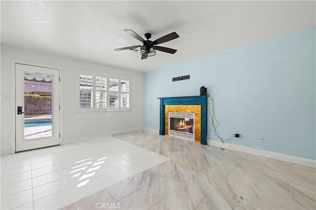 living room with a tile fireplace, ceiling fan, and a textured ceiling