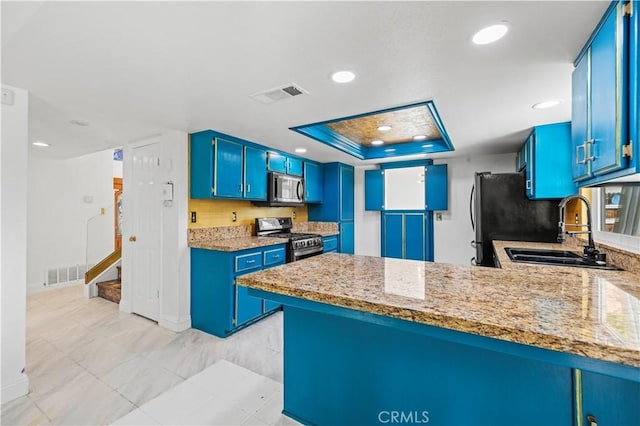 kitchen with blue cabinetry, sink, kitchen peninsula, a tray ceiling, and appliances with stainless steel finishes