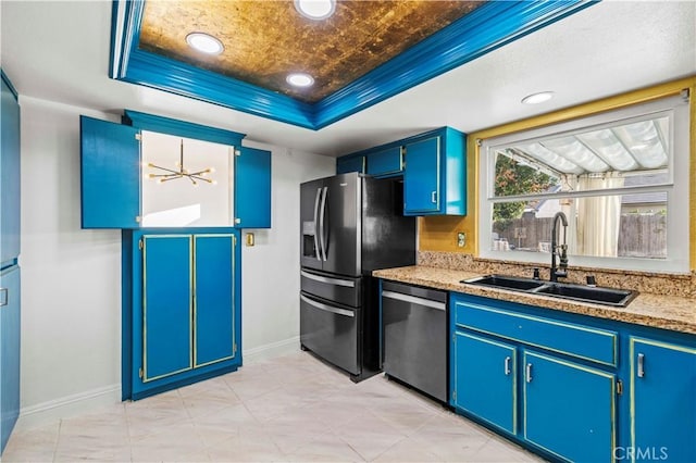 kitchen with appliances with stainless steel finishes, a tray ceiling, blue cabinets, sink, and a notable chandelier