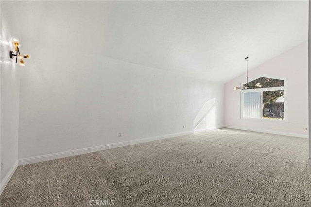 carpeted spare room with high vaulted ceiling and an inviting chandelier