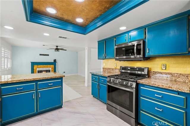 kitchen with stainless steel appliances, blue cabinets, a tray ceiling, and crown molding