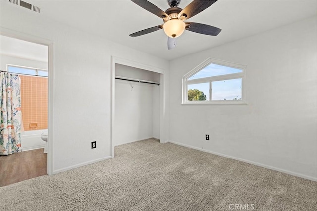 unfurnished bedroom with ceiling fan, light colored carpet, ensuite bath, and a closet