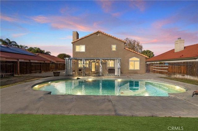 pool at dusk with a patio area