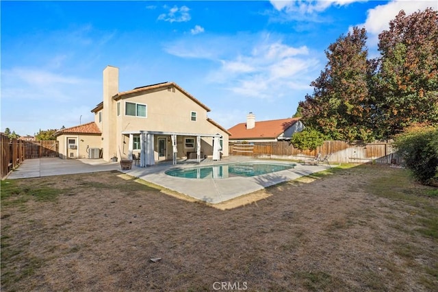 rear view of property featuring a fenced in pool and a patio