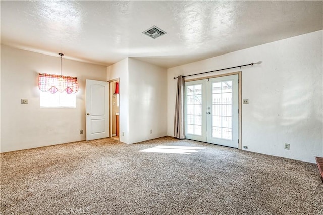 carpeted spare room featuring french doors and a textured ceiling