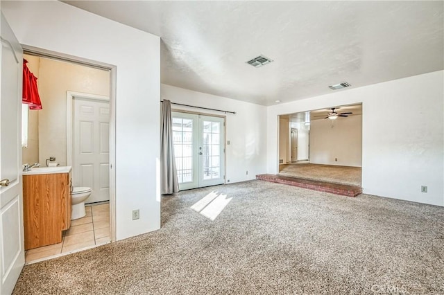 spare room with light carpet, french doors, and ceiling fan