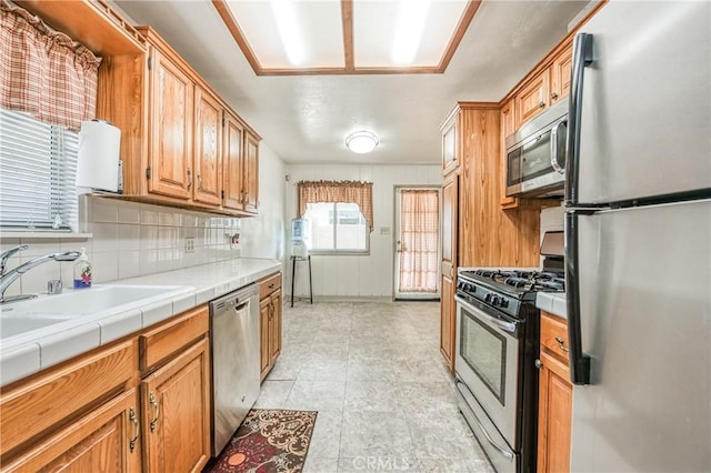 kitchen with tasteful backsplash, tile countertops, sink, and appliances with stainless steel finishes