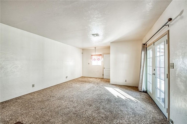 carpeted spare room featuring french doors and a barn door