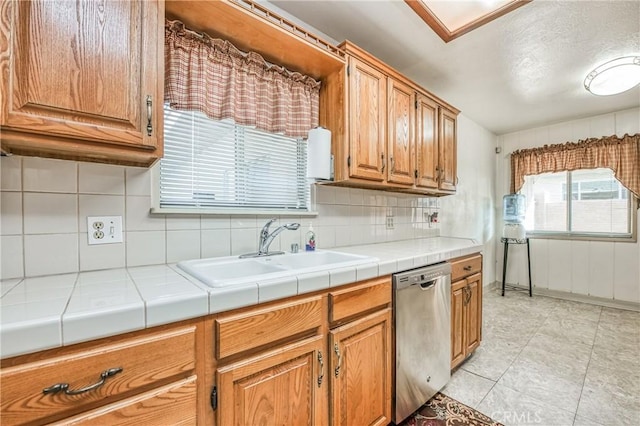 kitchen featuring backsplash, sink, light tile patterned floors, tile countertops, and dishwasher