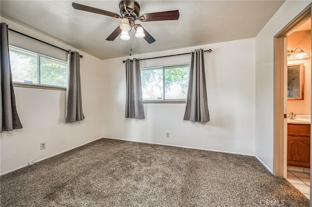 carpeted empty room with a wealth of natural light and ceiling fan