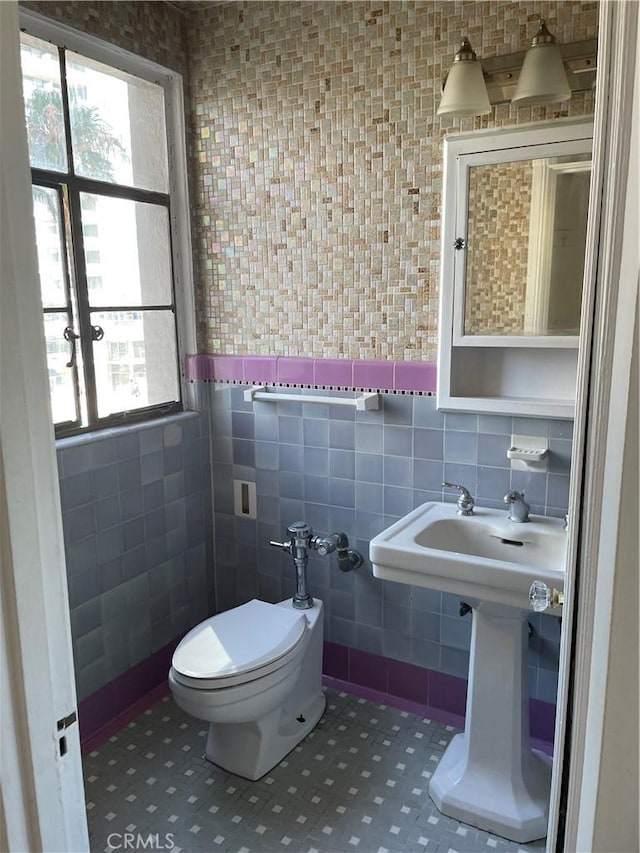 half bath featuring tile walls, toilet, and a healthy amount of sunlight