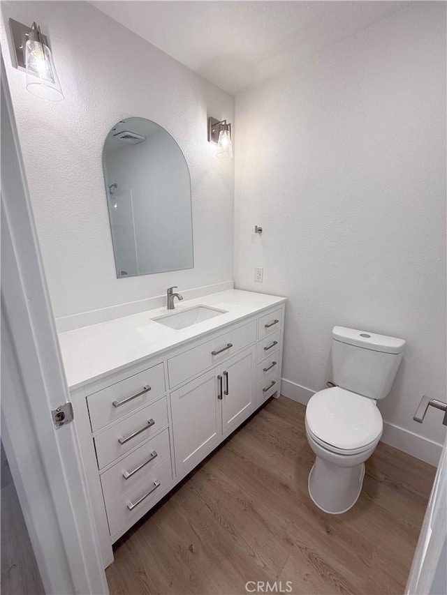 bathroom with hardwood / wood-style floors, vanity, and toilet