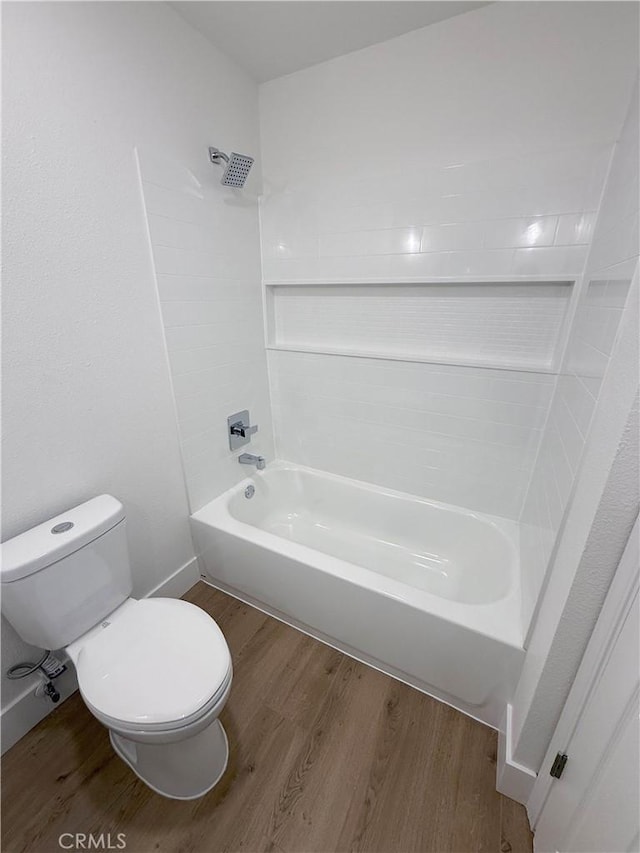 bathroom featuring wood-type flooring, bathing tub / shower combination, and toilet