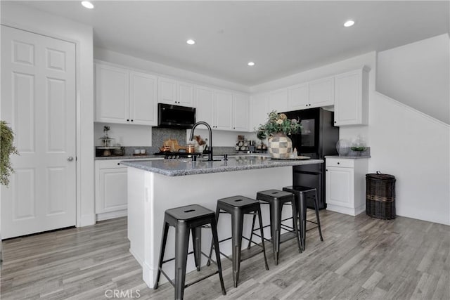 kitchen featuring a center island with sink and white cabinetry