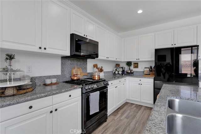 kitchen featuring backsplash, black appliances, white cabinets, light hardwood / wood-style floors, and light stone counters