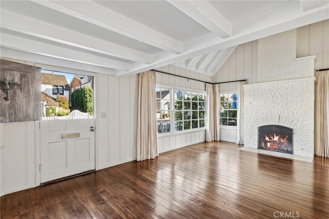 unfurnished living room with a brick fireplace, hardwood / wood-style floors, and beamed ceiling