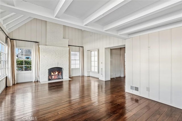 unfurnished living room with dark wood-type flooring, a brick fireplace, and vaulted ceiling with beams