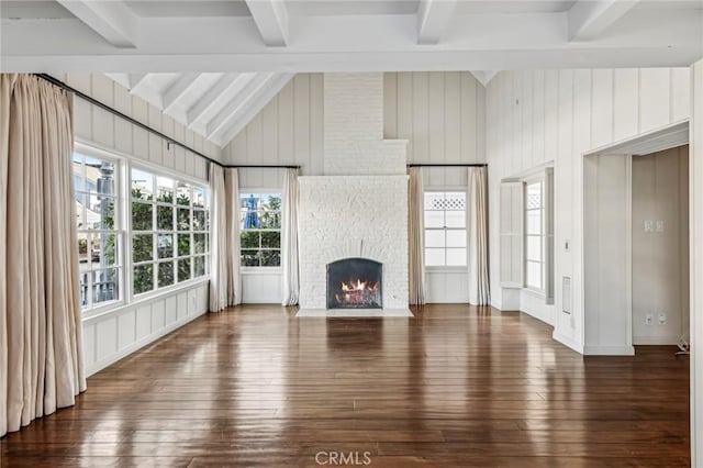 unfurnished living room featuring lofted ceiling with beams, a fireplace, dark hardwood / wood-style flooring, and wooden walls