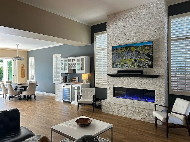 living room featuring wood-type flooring, a stone fireplace, beverage cooler, and ornamental molding